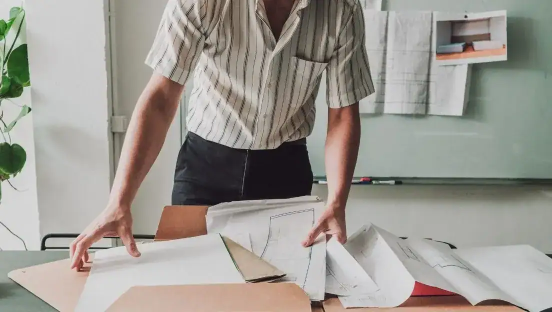 STanding Man looking at architect papers on a table